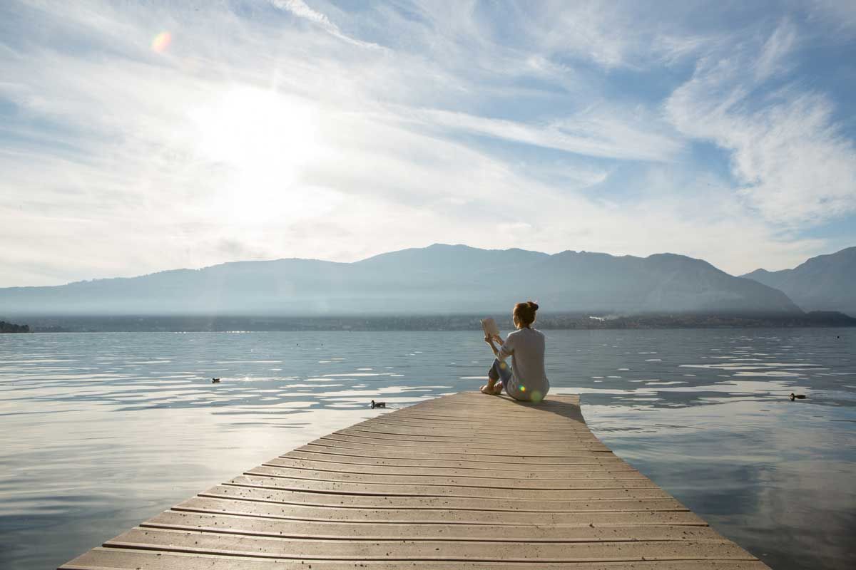 woman sitting on dock reading a book